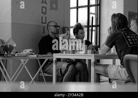 Monochrome d'un groupe de convives appréciant un repas à l'intérieur de Taqueria Paloma, avec un petit chien assis sur les genoux d'un homme Banque D'Images