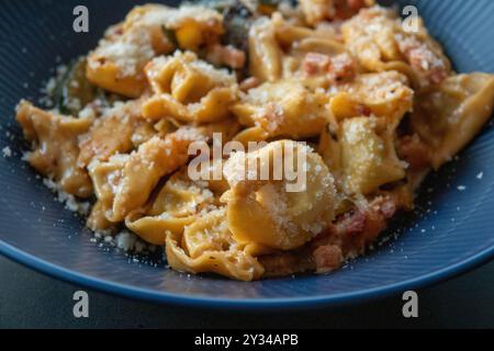 Plat de pâtes farcies Tortellini avec sauce et saupoudré de parmesan. Gros plan avec mise au point sélective et faible profondeur de champ. Banque D'Images