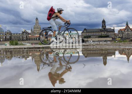 La silhouette de Dresde avec un cycliste et des nuages sombres derrière l'église notre-Dame se reflète dans une flaque sur la piste cyclable de l'Elbe, piste cyclable de l'Elbe, Banque D'Images