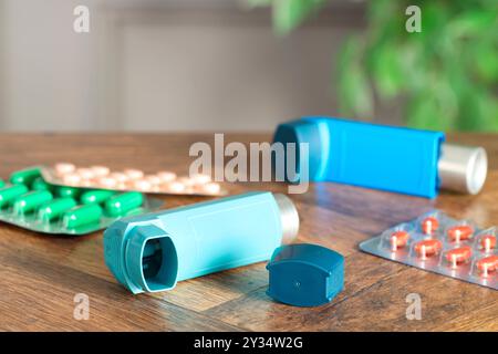 Inhalateurs et pilules sur la table en bois à l'intérieur, gros plan. Traitement de l'asthme Banque D'Images