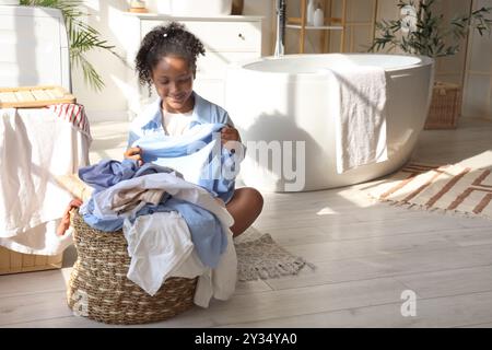 Adolescente afro-américaine avec buanderie dans la salle de bains Banque D'Images