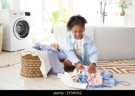 Adolescente afro-américaine avec buanderie dans la salle de bains Banque D'Images