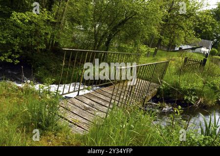 Passerelle en bois et fer sur un cours d'eau dans un paysage de campagne Banque D'Images