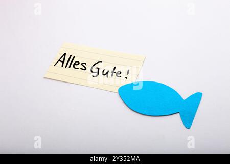 Alles Gute ! Mot de souhait allemand pour la communion sur un papier beige, écrit à la main. Poisson bleu dans le coin. Isolé sur blanc. Espace libre pour le texte. Banque D'Images