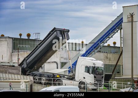 Camion blanc moderne déversant du sable à côté de la bande transporteuse dans le dépôt de matériaux de construction industriels au port de Murkan sur l'île de Rugen, Baltique Banque D'Images