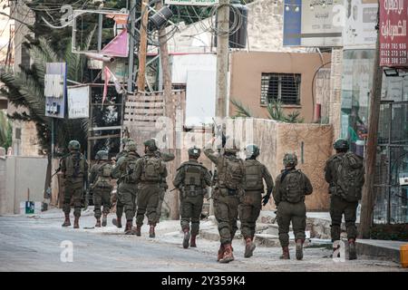 Tubas, Cisjordanie, Palestine. 11 septembre 2024. Un soldat israélien visant tandis que les autres descendent dans le centre-ville de Tubas lors du raid sur la ville de Tubas. Un raid militaire israélien de grande envergure contre la ville de Tubas, dans le nord de la Cisjordanie occupée, a permis de tuer cinq Palestiniens dans une frappe aérienne et les forces ont encerclé un hôpital palestinien et empêché le personnel médical de transporter des patients. (Crédit image : © Nasser Ishtayeh/SOPA images via ZUMA Press Wire) USAGE ÉDITORIAL SEULEMENT! Non destiné à UN USAGE commercial ! Banque D'Images