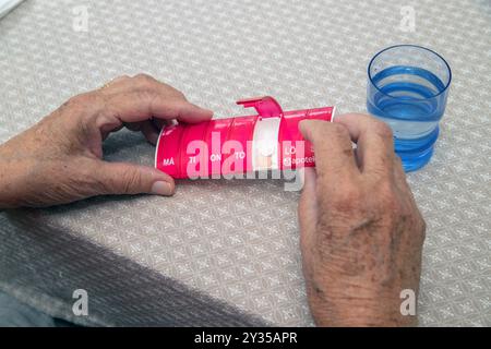 Gros plan de la main âgée femelle prenant des médicaments de la boîte de pilules médicales, pilules de tri. Les doses quotidiennes d'une semaine de médicament sont placées dans la boîte de dose hebdomadaire Banque D'Images