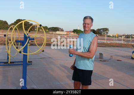 Un homme plus âgé hispanique faisant un exercice externe de rotation de l'épaule avec des poids légers pour la douleur Banque D'Images