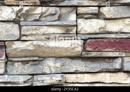 Fond abstrait présente un arrangement de pierres superposées, avec des teintes grises avec des touches de rouge profond, créant une perfe de toile moderne et texturée Banque D'Images