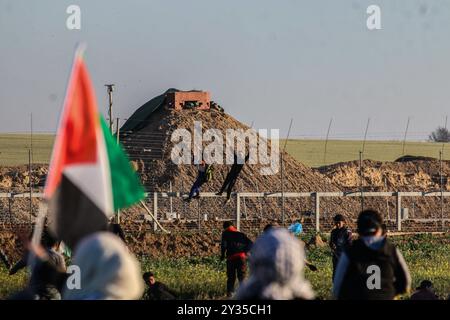 Gaza, Palestine, 8 mars 2019. Des manifestants palestiniens brûlent des pneus et brandissent le drapeau palestinien, quelques pierres lançant vers la clôture, dans la zone de Malika, à l'est de la bande de Gaza. Des manifestants palestiniens s’étaient rassemblés sur différents sites le long de la frontière Gaza-Israël lors de ce vendredi 50ème rassemblement de la Grande Marche du retour, et selon le ministère de la santé à Gaza cinq Palestiniens ont été blessés en ce vendredi mars, dont un dans un état critique. Selon l’armée israélienne, des ballons incendiaires transportant des explosifs ont été lâchés de la bande de Gaza dans le sud d’Israël. La plus haute Comm Banque D'Images