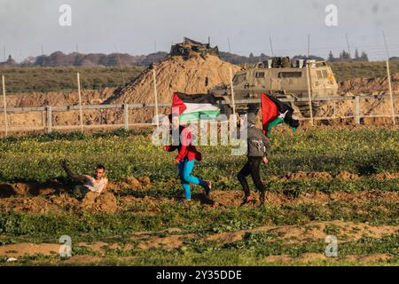 Gaza, Palestine, 8 mars 2019. Des manifestants palestiniens brûlent des pneus et brandissent le drapeau palestinien, quelques pierres lançant vers la clôture, dans la zone de Malika, à l'est de la bande de Gaza. Des manifestants palestiniens s’étaient rassemblés sur différents sites le long de la frontière Gaza-Israël lors de ce vendredi 50ème rassemblement de la Grande Marche du retour, et selon le ministère de la santé à Gaza cinq Palestiniens ont été blessés en ce vendredi mars, dont un dans un état critique. Selon l’armée israélienne, des ballons incendiaires transportant des explosifs ont été lâchés de la bande de Gaza dans le sud d’Israël. La plus haute Comm Banque D'Images