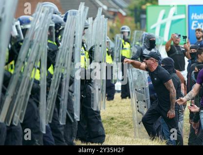 Photo du dossier datée du 04/08/24 de Morgan Hardy (à droite) confronté à des policiers alors que des troubles ont éclaté pendant une manifestation anti-immigration devant le Holiday Inn Express à Rotherham, South Yorkshire. Morgan Hardy qui a été emprisonné pendant trois ans après que le juge a entendu comment il a jeté des panneaux de clôture, un extincteur et une chaise à la file d'officiers devant le Holiday Inn Express à Rotherham. Le tribunal a entendu dire qu'il faisait partie d'un groupe criant « nous voulons que notre pays revienne » et qu'il pouvait être vu sur des images devant la foule, raillant les officiers les bras tendus. Date d'émission : jeudi Septemb Banque D'Images