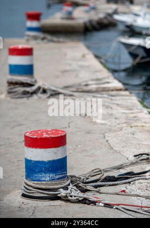 bornes sur un mur du port avec des cordes et des fils pour attacher les navires et les bateaux peints en rouge blanc et bleu Banque D'Images