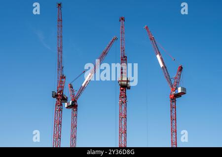 Quatre grues à tour rouges vues sur un chantier de construction à Berlin, en Allemagne Banque D'Images