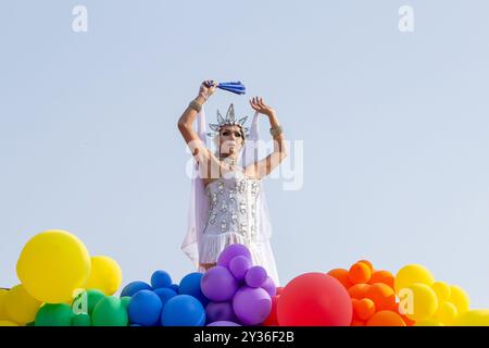 Goiânia GOIAS BRÉSIL - 08 SEPTEMBRE 2024 : une personne LGBT, vêtue de blanc avec un char décoré de ballons, danse, à la LGBT Pride Parad 2024 Banque D'Images