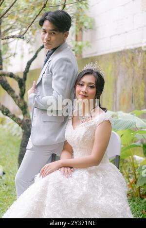 une paire d'homme et de femme poses élégantes debout assis détendu poses formelles portant de belles robes dans un parc photo shoot appareil photo en gros plan. s/o Banque D'Images