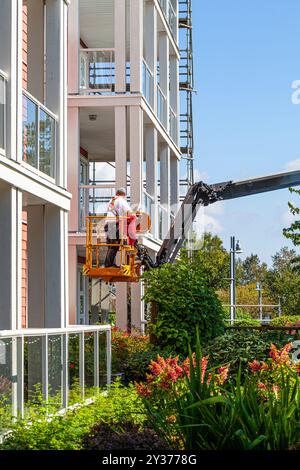 Exploitant utilisant un monte-personne pour accéder aux balcons d'un immeuble à appartements à Steveston Colombie-Britannique Canada Banque D'Images