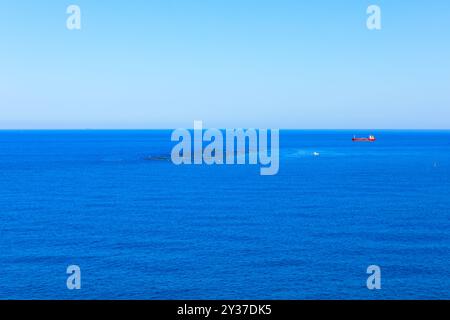 Le bateau rouge navigue dans l'océan. Mer bleue et ciel avec espace de copie. Le bateau flotte paisiblement sur le vaste océan, entouré de douces vagues Banque D'Images