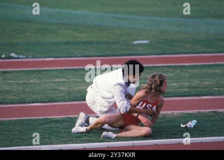 20 août 1984 ; Los Angeles, CA, États-Unis ; lors de la finale olympique de 1984, lors du 3 000 mètres, MARY DECKER s'est mêlée à Zola Budd, une originaire d'Afrique du Sud qui courait pour la Grande-Bretagne. Decker trébucha, tomba sur le champ et se blessa à la hanche. Photo : DECKER est aidé hors du champ. Credit : Arthur Grace/ZUMAPRESS.com/Alamy Live News Banque D'Images