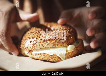 Dégustez un bagel au sésame fraîchement préparé avec du fromage à la crème sur une planche de bois, parfait pour tous les repas Banque D'Images