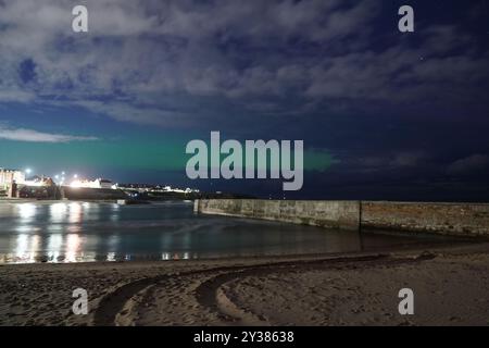 Les aurores boréales exposées dans le ciel de Cullercoats Bay à North Tyneside, sur la côte nord-est de l'Angleterre, jeudi soir. Les lumières, également connues sous le nom d'aurores boréales, étaient visibles dans certaines parties de l'Écosse, de l'Irlande du Nord et du nord de l'Angleterre. Les aurores apparaissent lorsque des particules chargées entrent en collision avec des gaz dans l'atmosphère terrestre autour des pôles magnétiques. Date de la photo : jeudi 12 septembre 2024. Banque D'Images