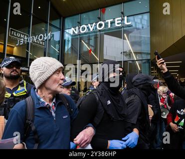 Melbourne, Australie. 11 septembre 2024. Les manifestants relient les armes devant une entrée endommagée par la peinture Un blocus planifié et une manifestation contre Land Forces 2024, la plus grande exposition de l'industrie de la défense dans l'hémisphère sud, ont éclaté en affrontements avec la police tout au long de la journée. Les manifestants tentant d'empêcher l'entrée de la convention ont jeté des objets et des liquides sur les officiers, construit de petits barrages et déclenché des incendies de poubelles, tandis que la police a utilisé la force, le gaz poivré, les grenades lacrymogènes, les grenades paralysantes et les balles en caoutchouc sur les manifestants crédit : SOPA images Limited/Alamy Live News Banque D'Images