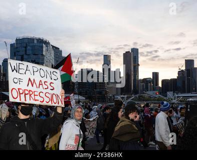 Melbourne, Australie. 11 septembre 2024. Un anti-armes vu alors que le soleil se lève au-dessus des gratte-ciel de Melbourne, Un blocus planifié et une manifestation contre Land Forces 2024, la plus grande exposition de l'industrie de la défense de l'hémisphère sud, ont éclaté en affrontements avec la police tout au long de la journée. Les manifestants tentant d'empêcher l'entrée de la convention ont jeté des objets et des liquides sur les officiers, construit de petits barrages et déclenché des incendies de poubelles, tandis que la police a utilisé la force, le gaz poivré, les grenades lacrymogènes, les grenades paralysantes et les balles en caoutchouc sur les manifestants crédit : SOPA images Limited/Alamy Live News Banque D'Images