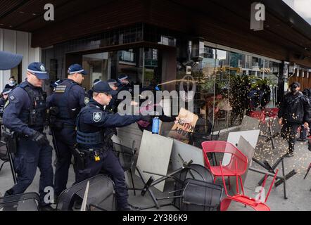 Des agents de la police de Nouvelle-Galles du Sud amenés à Melbourne pour la manifestation sont vus déployer du capsicum pulvérisant sur une barricade des manifestants fabriqués à partir de meubles de salle à manger d'un café Un blocus planifié et une manifestation contre Land Forces 2024, la plus grande exposition de l'industrie de la défense dans l'hémisphère sud, ont éclaté dans des affrontements avec la police tout au long de la journée. Les manifestants qui tentaient d'empêcher l'entrée de la convention ont jeté des objets et des liquides sur les officiers, construit de petits barrages et déclenché des incendies d'ordures, tandis que la police a utilisé la force, le gaz poivre, les grenades lacrymogènes, les grenades paralysantes et les balles en caoutchouc sur la manifestation Banque D'Images