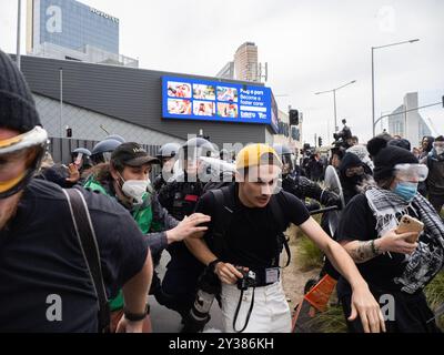 Melbourne, Australie. 11 septembre 2024. Les manifestants et les médias fuient une ligne de police qui avance Un blocus planifié et une manifestation contre Land Forces 2024, la plus grande exposition de l'industrie de la défense dans l'hémisphère sud, ont éclaté en affrontements avec la police tout au long de la journée. Les manifestants tentant d'empêcher l'entrée de la convention ont jeté des objets et des liquides sur les officiers, construit de petits barrages et déclenché des incendies de poubelles, tandis que la police a utilisé la force, le gaz poivré, les grenades lacrymogènes, les grenades paralysantes et les balles en caoutchouc sur les manifestants crédit : SOPA images Limited/Alamy Live News Banque D'Images