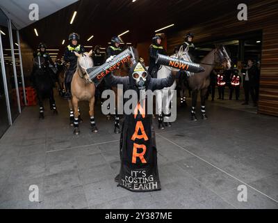 Un manifestant en costume tient un support de missile cassé lisant : « CESSEZ-LE-FEU MAINTENANT ! » Devant une ligne de chevaux de la police, Un blocus planifié et une manifestation contre les Forces terrestres 2024, la plus grande exposition de l'industrie de la défense dans l'hémisphère sud, ont éclaté en affrontements avec la police tout au long de la journée. Les manifestants tentant d'empêcher l'entrée de la convention ont jeté des objets et des liquides sur les policiers, construit de petits barrages et déclenché des incendies de poubelles, tandis que la police a utilisé la force, le gaz poivre, les gaz lacrymogènes, les grenades paralysantes et les balles en caoutchouc sur les manifestants (photo Alex Zucco/SOPA images/Sipa USA) Banque D'Images