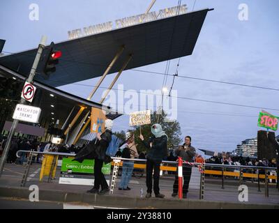 Le panneau du Melbourne Exhibition Centre est visible au-dessus de quelques manifestants au début du rassemblement. Un blocus planifié et une manifestation contre Land Forces 2024, la plus grande exposition de l'industrie de la défense dans l'hémisphère sud, ont éclaté en affrontements avec la police tout au long de la journée. Les manifestants qui tentaient d'empêcher l'entrée de la convention ont jeté des objets et des liquides sur les officiers, construit de petits barrages et déclenché des incendies d'ordures, tandis que la police a utilisé la force, le gaz poivre, les gaz lacrymogènes, les grenades paralysantes et les balles en caoutchouc sur les manifestants. (Photo Alex Zucco/SOPA images/SIPA USA) Banque D'Images