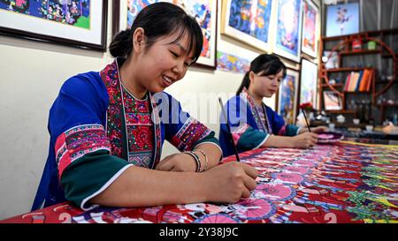 Liuzhou, région autonome chinoise de Guangxi Zhuang. 11 septembre 2024. Les artistes fermiers Chen Meimei (à gauche) et Rong Xuelian travaillent sur une peinture dans un atelier dans le comté autonome de Sanjiang Dong de Liuzhou, dans la région autonome de Guangxi Zhuang au sud de la Chine, 11 septembre 2024. Une exposition présentant des peintures de fermiers a débuté ici jeudi. Dans le comté autonome de Sanjiang Dong de Liuzhou, plus de 600 artistes fermiers sont engagés dans l'industrie de la peinture. Crédit : Zhang Ailin/Xinhua/Alamy Live News Banque D'Images
