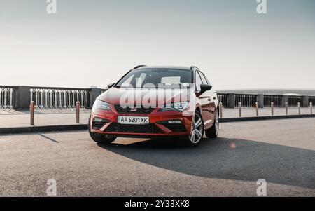 Red Leon Cupra garé sur le front de mer au lever du soleil. Le soleil matinal brille à la sporty SEAT wagon sur le parking. Banque D'Images