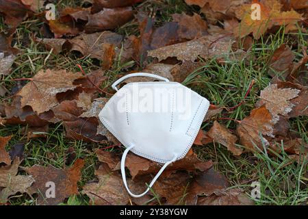 Un respirateur médical usagé mais propre repose sur le sol dans l'herbe et les feuilles d'automne dans le givre. Fin de l'automne, début de l'hiver, gel. Banque D'Images