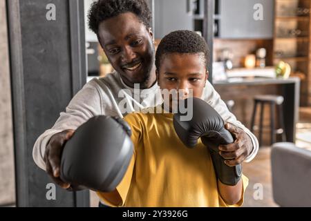 Père afro-américain et fils s'amusant ensemble, boxe. Banque D'Images