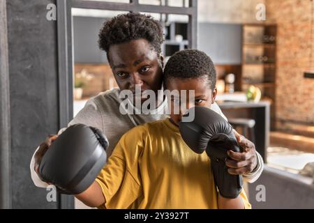 Père afro-américain et fils s'amusant ensemble, boxe. Banque D'Images