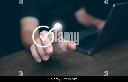 Un homme tapant le doigt sur le signe lumineux correct, représentant une approbation pour un document, un projet d'entreprise, et une évaluation ou une évaluation Banque D'Images