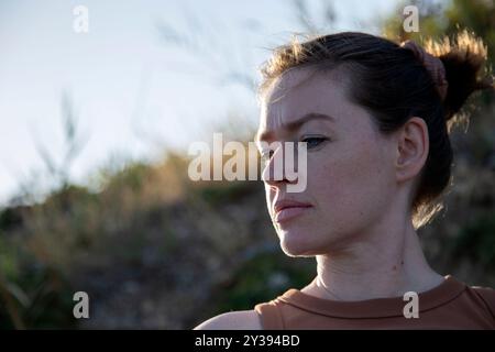 Portrait d'une jeune femme aux cheveux bruns et aux yeux bleus à l'extérieur Banque D'Images