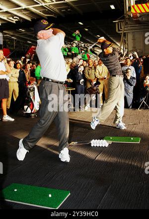 Golfe Arabique (3 mars 2004) – Mark O’Meara, à gauche, et Tiger Woods, à droite, conduisent des balles de golf par une porte du pont de la baie du hangar normalement utilisée pour accéder à un ascenseur d’avion à bord de l’USS George Washington (CVN 73). Banque D'Images