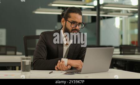 Occupé concentré indien employeur masculin entreprise entrepreneur arabe patron PDG homme d'affaires musulman homme d'affaires au bureau avec ordinateur portable de travail Banque D'Images