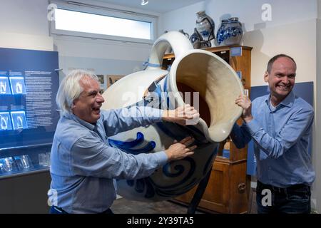 Hanau, Allemagne. 13 septembre 2024. Les presseurs de pommes Jörg Stier (à gauche) et Martin Heil tiennent un 'Faulenzer', un bembel en grès surdimensionné pour le cidre. Les producteurs de cidre ouvrent la saison 2024 sous la devise « les pommes appartiennent à un verre ». Crédit : Helmut Fricke/dpa/Alamy Live News Banque D'Images