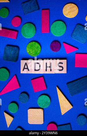 Texte ADHD en lettres ADHS de lanugage allemande sur blocs de bois et fond chaotique, photo verticale Banque D'Images