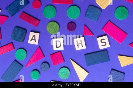 Texte ADHD en lettres ADHS de lanugage allemande sur blocs de bois et fond chaotique Banque D'Images