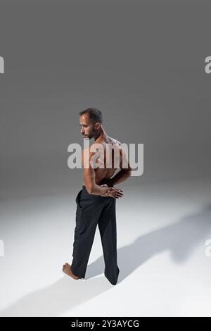 Photo vue d'angle, homme regardant par-dessus l'épaule, ses muscles du dos définis dans une lumière douce. Son langage corporel transmet la force tranquille et la réflexion. Banque D'Images