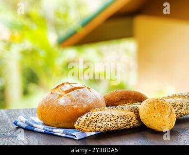 Pain frais et serviette à carreaux sur table en bois sur fond rural. Banque D'Images