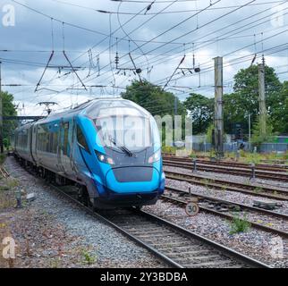 Un train bleu épuré roule le long des voies sous un ciel nuageux, mettant en valeur le transport contemporain et le voyage dynamique. Parfait pour les thèmes de l'INF moderne Banque D'Images