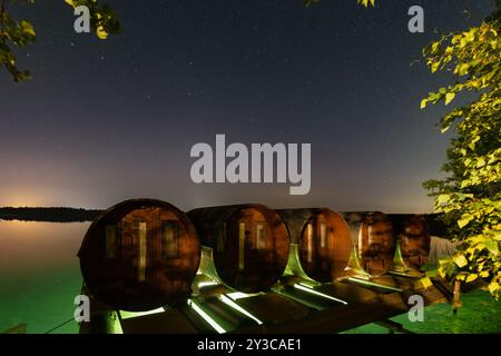 Photo de nuit, ciel étoilé clair, tonneaux d'une maison sur l'eau sur le lac Rummu. Banque D'Images