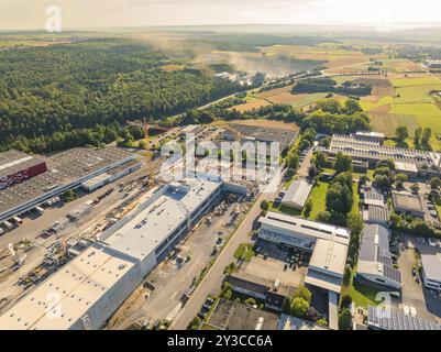 Vue plongeante d'une zone industrielle avec grues de construction et bâtiments d'usine, entourée d'arbres et de routes, zone industrielle Wolfsberg, Nago Banque D'Images