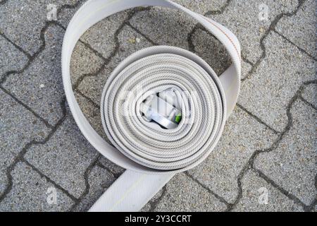 Tuyau d'incendie enroulé avec boucle en métal sur sol pavé, pompiers, Enzkloesterle, Forêt Noire, Allemagne, Europe Banque D'Images