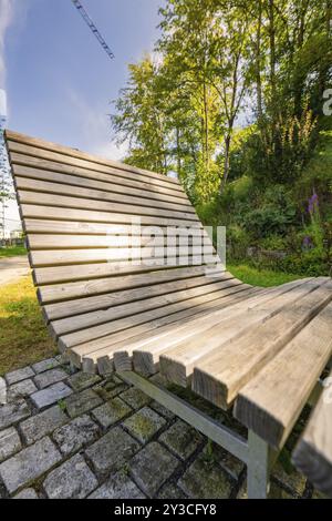 Banc en bois moderne dans un parc ensoleillé, entouré d'arbres verts et de plantes, vous invite à la détente, Nagold, Forêt Noire, Allemagne, Europe Banque D'Images